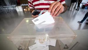 Un elector deposita su voto en la urna en unas elecciones catalanas.