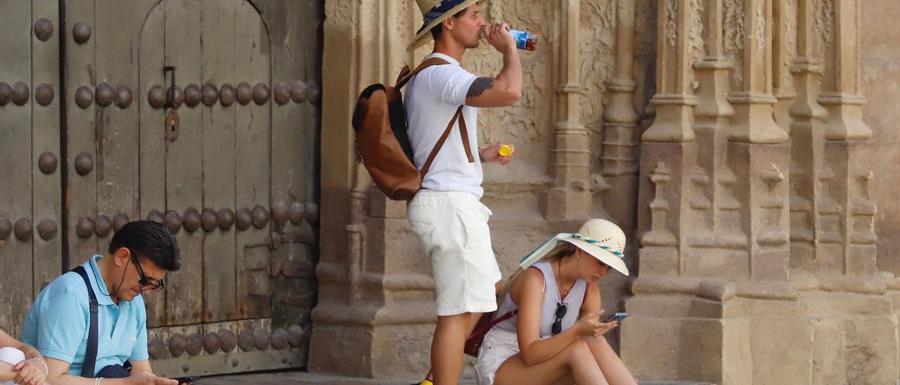 Un turista se hidrata mientras se resguarda del sol.