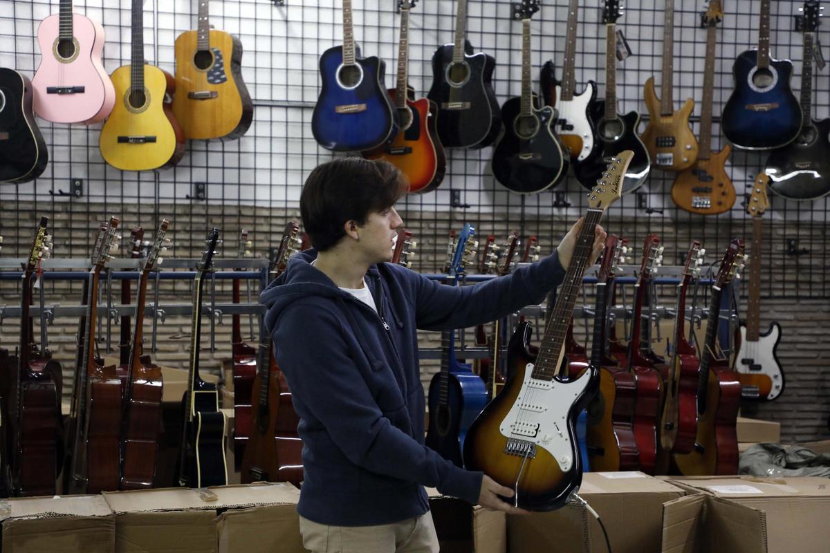 Un trabajador joven enseña una guitarra en un comercio de música, en una imagen de archivo.