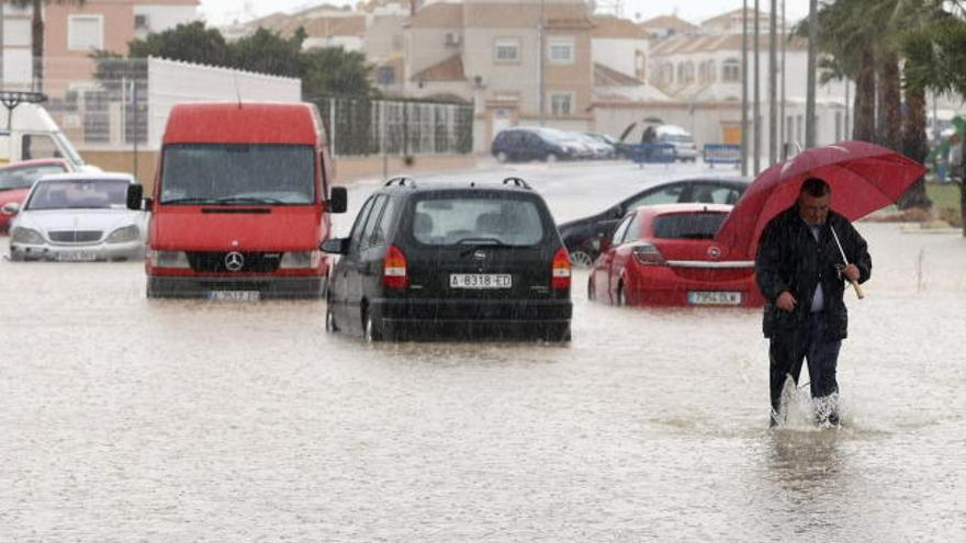 Un hombre abandona su coche atrapado en una calle anegada por los efectos de las lluvias intensas en el litoral sur de la provincia de Alicante que, según la previsión de la Agencia Estatal de Meteorología (AEMET) podrían acumular 110 litros por metro cuadrado en doce horas.