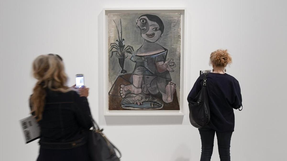 Dos visitantes miran el cuadro de Picasso 'Niño con langosta', en la muestra sobre cocina del pintor malagueño, en el Museu Picasso.