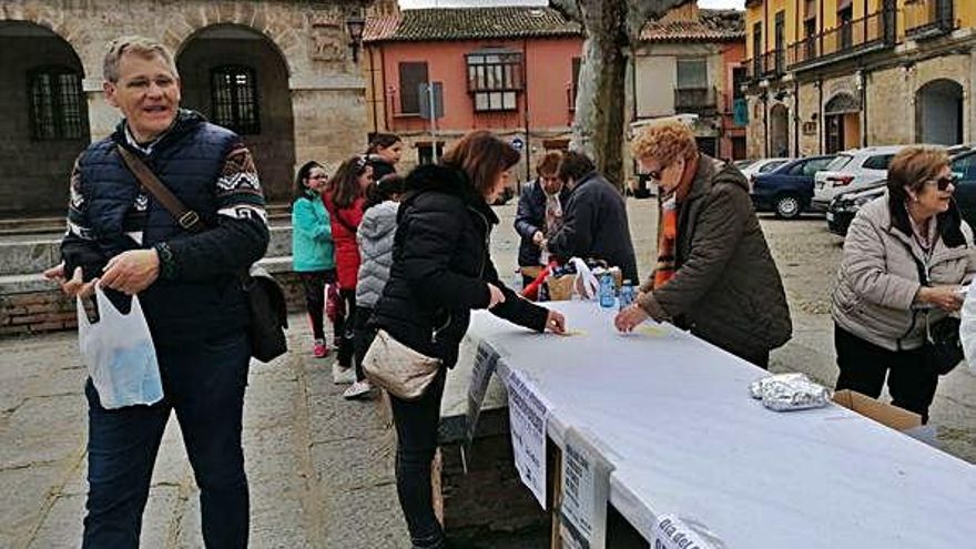 Voluntarias de Manos Unidas reparten bocadillos y una botella de agua entre los toresanos en la Plaza Mayor.