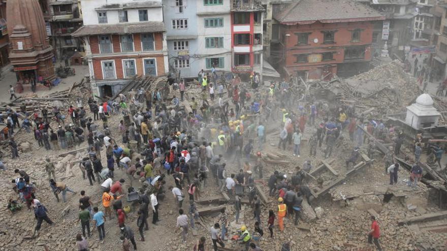 Varias personas buscan supervivientes entre los escombros tras un terremoto en Katmandú.