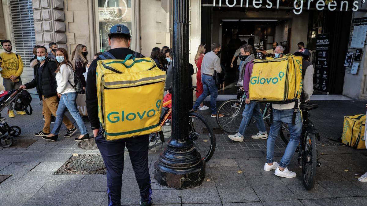 Repartidores de Glovo esperan delante de un restaurante en Barcelona.