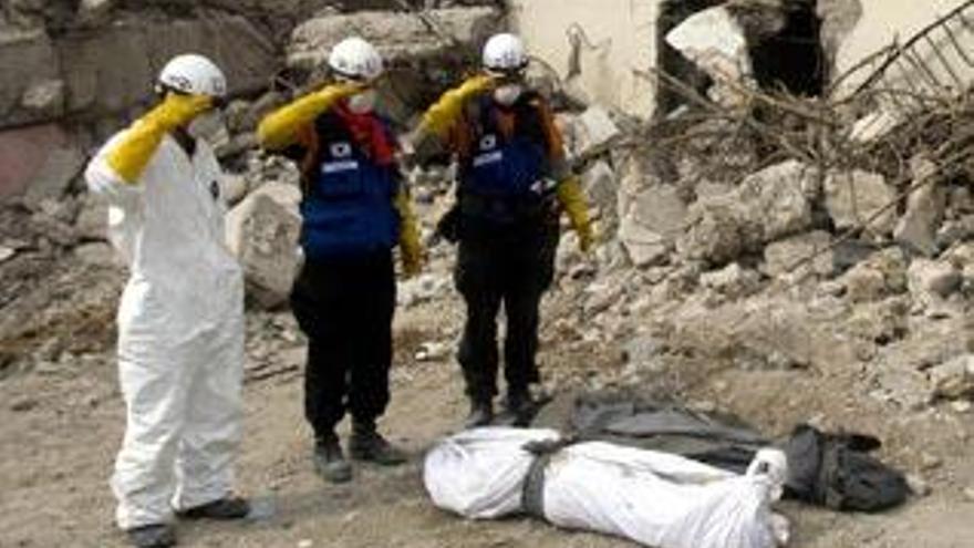 Tres miembros de un equipo de rescate de Corea del Sur, ante dos cadáveres, este martes en Puerto Príncipe.