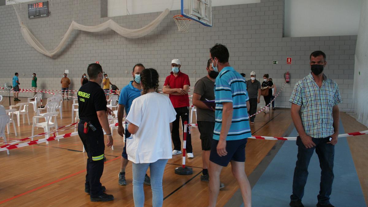 Un voluntario de Protección Civil ordena el público para vacunarse.