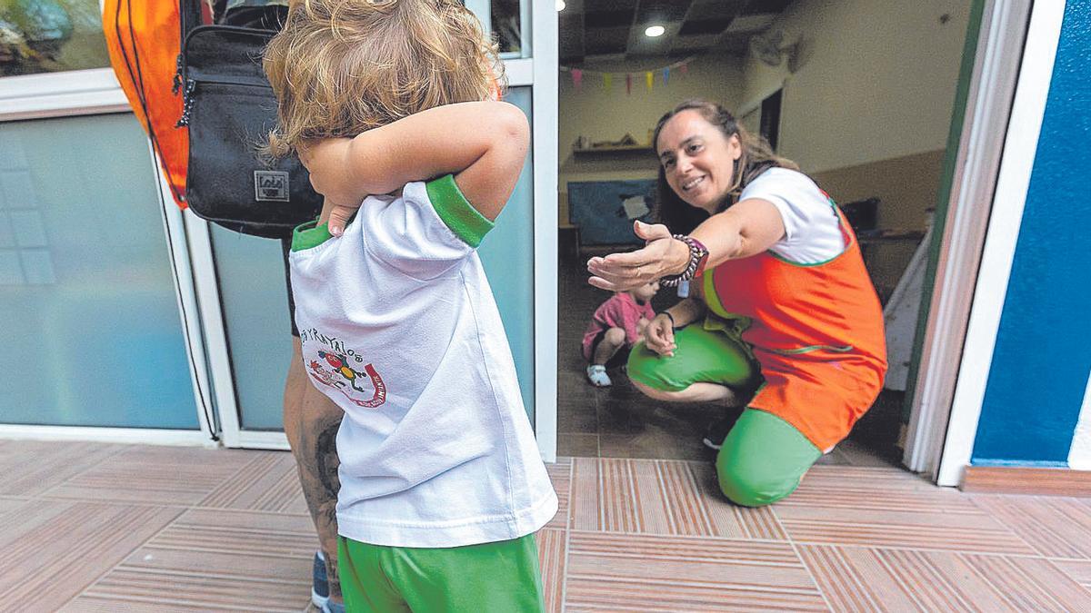 Una educadora llama a un alumno a la entrada de una escuela infantil.
