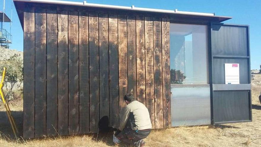 Un operario realiza labores de pintura en el pabellón de vigilancia del recinto arqueológico de los astures en Arrabalde.