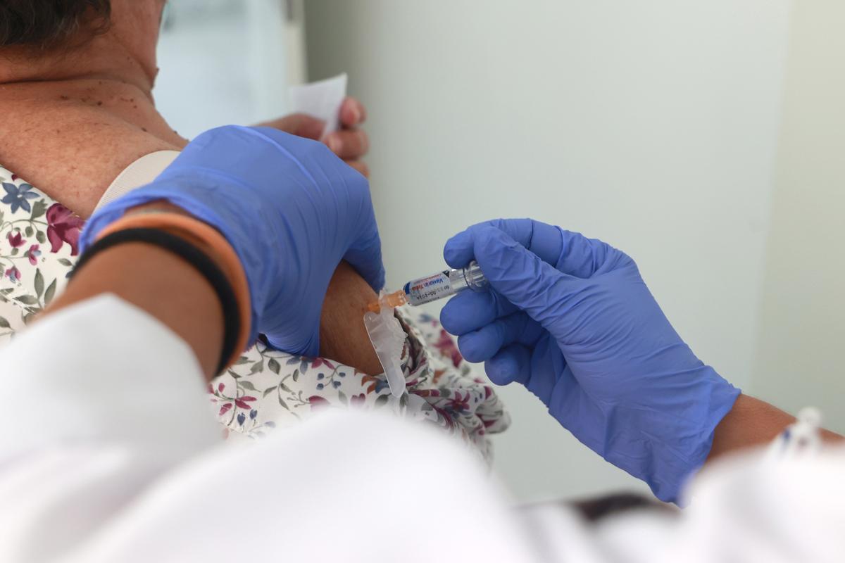 Archivo - Una mujer se vacuna contra la gripe y la Covid-19
