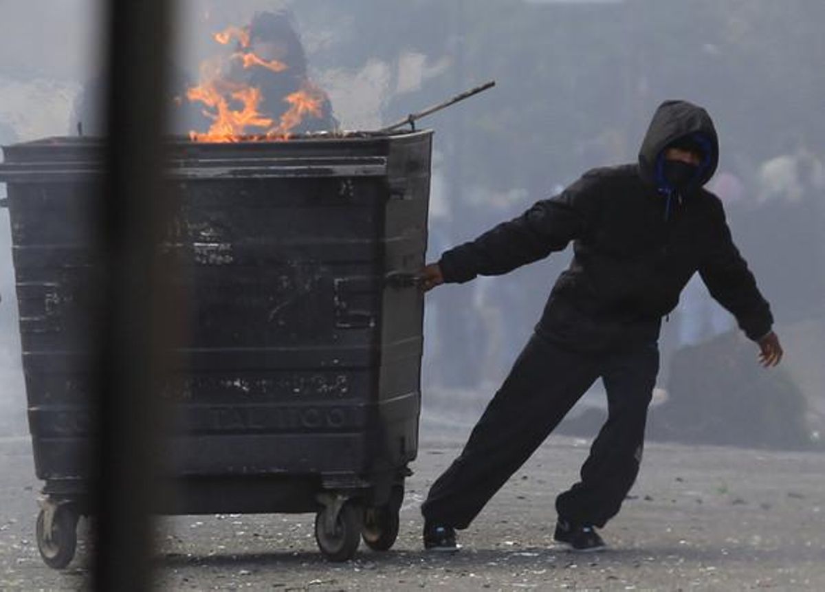 Un encaputxat arrossega un contenidor incendiat durant els disturbis a Hackney, a l’est de Londres (Anglaterra).