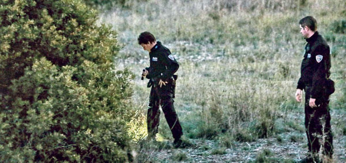 Dos policías locales examinan un campo de Son Ferrer en busca de pistas sobre la joven desaparecida.