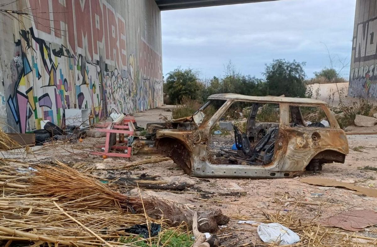 Un vehículo calcinado y enseres bajo el puente de la autopista en el cauce de la rambla.  | D.PAMIES