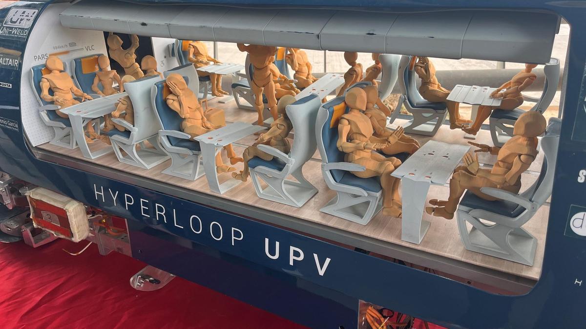 Maqueta de un tren Hyperloop de la UPV con figuras de personas sentadas en su interior.