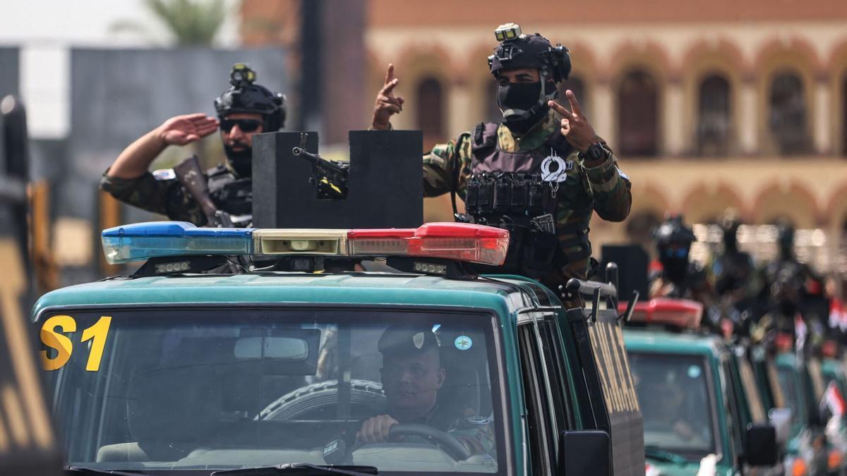 Miembros de las fuerzas de seguridad de Irak hacen el signo de la victoria durante un desfile militar para celebrar la retirada militar de EEUU, este miércoles en Bagdad.