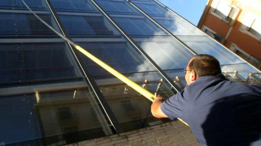 Un operario limpia los cristales del edificio del Ayuntamiento.