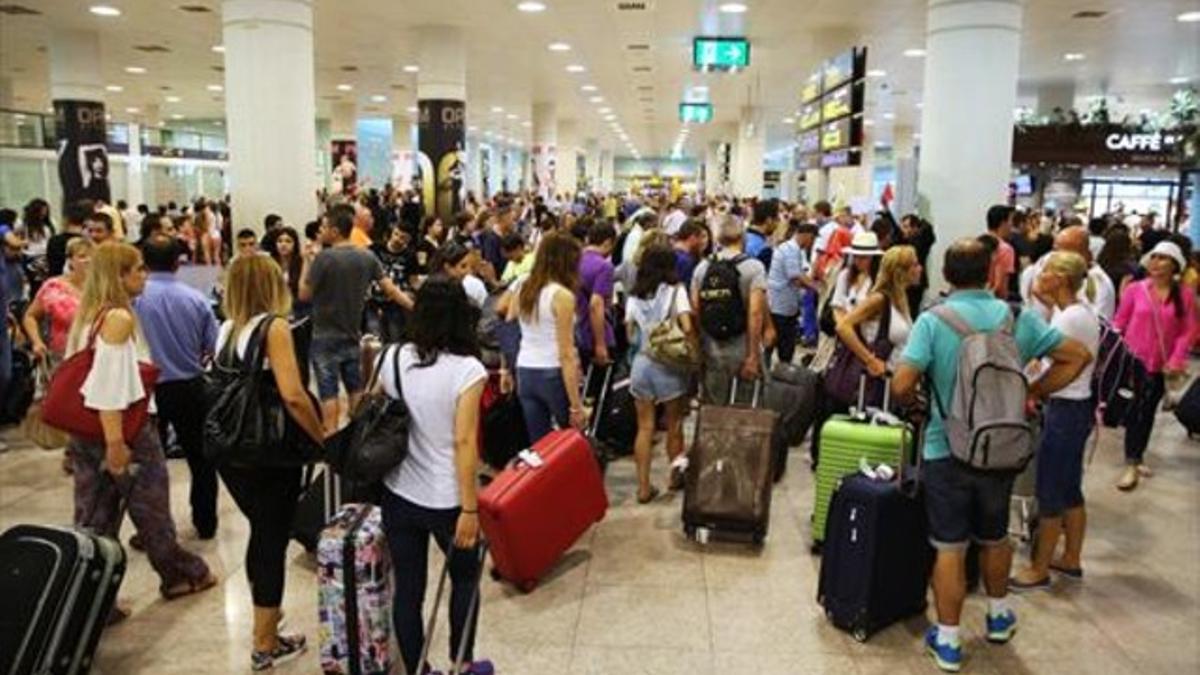 Decenas de pasajeros en el El Prat, ayer, en el primer día de operación salida.