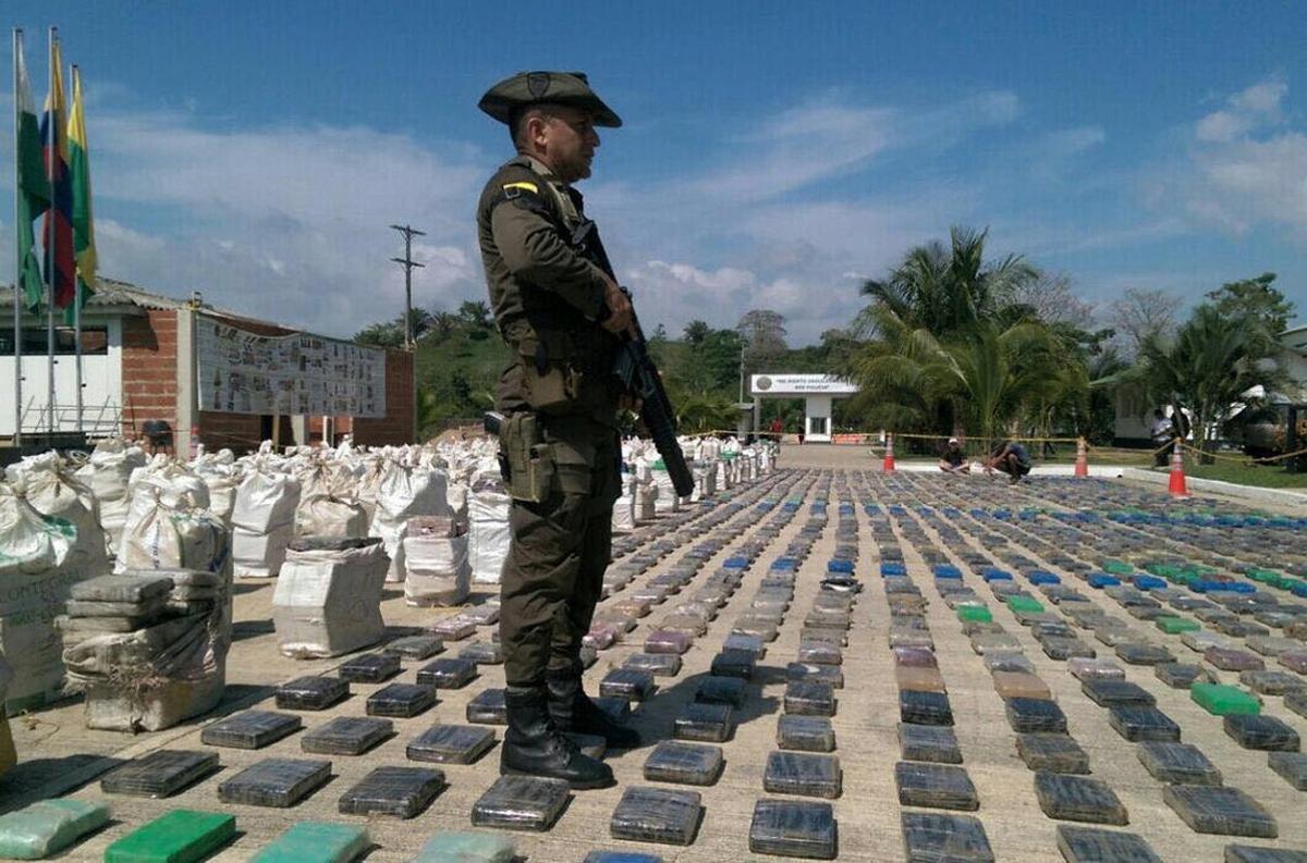 BOG802. TURBO (COLOMBIA), 15/05/2016.- Fotografía cedida por la Policía Antinarcóticos de Colombia de un integrante de la policía vigilando paquetes de droga incautados al hoy, domingo 15 de mayo de 2016, en Turbo (Colombia). Al menos ocho toneladas de cocaína fueron incautadas hoy por la Policía colombiana en el noroeste del país, decomiso que constituye el más grande en la historia, según el presidente colombiano, Juan Manuel Santos. La droga pertenecía a la banda criminal Clan Úsuga, la mayor del país, y fue encontrada en Turbo, municipio del departamento de Antioquia, en la región del Urabá, informó el Ministerio de Defensa. EFE/POLICÍA ANTINARCÓTICOS DE COLOMBIA/SOLO USO EDITORIAL/NO VENTAS