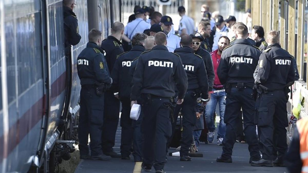 Danish police guard a train carrying migrants, mainly from Syria and Iraq, at Rodby train station, south of Denmark