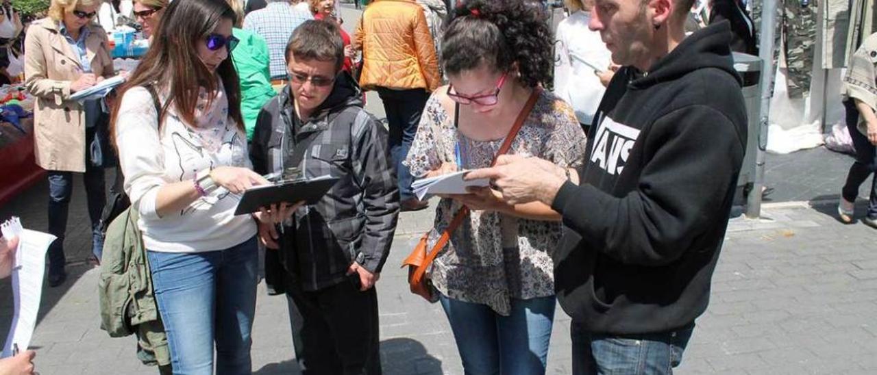 Voluntarios de &quot;Lugones en pie&quot; recogiendo firmas en el mercado semanal de la localidad.