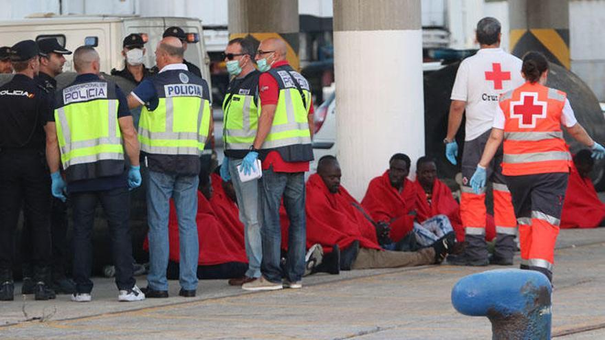 Agentes de la policía y miembros de Cruz roja atienden a unos inmigrantes llegados al puerto de Málaga.