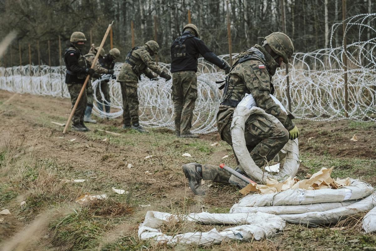 Soldados del ejército polaco arreglan bobinas de alambre de púas en una valla a lo largo de la frontera polaca, con el enclave ruso de Kaliningrado, cerca de Zerdziny, Polonia