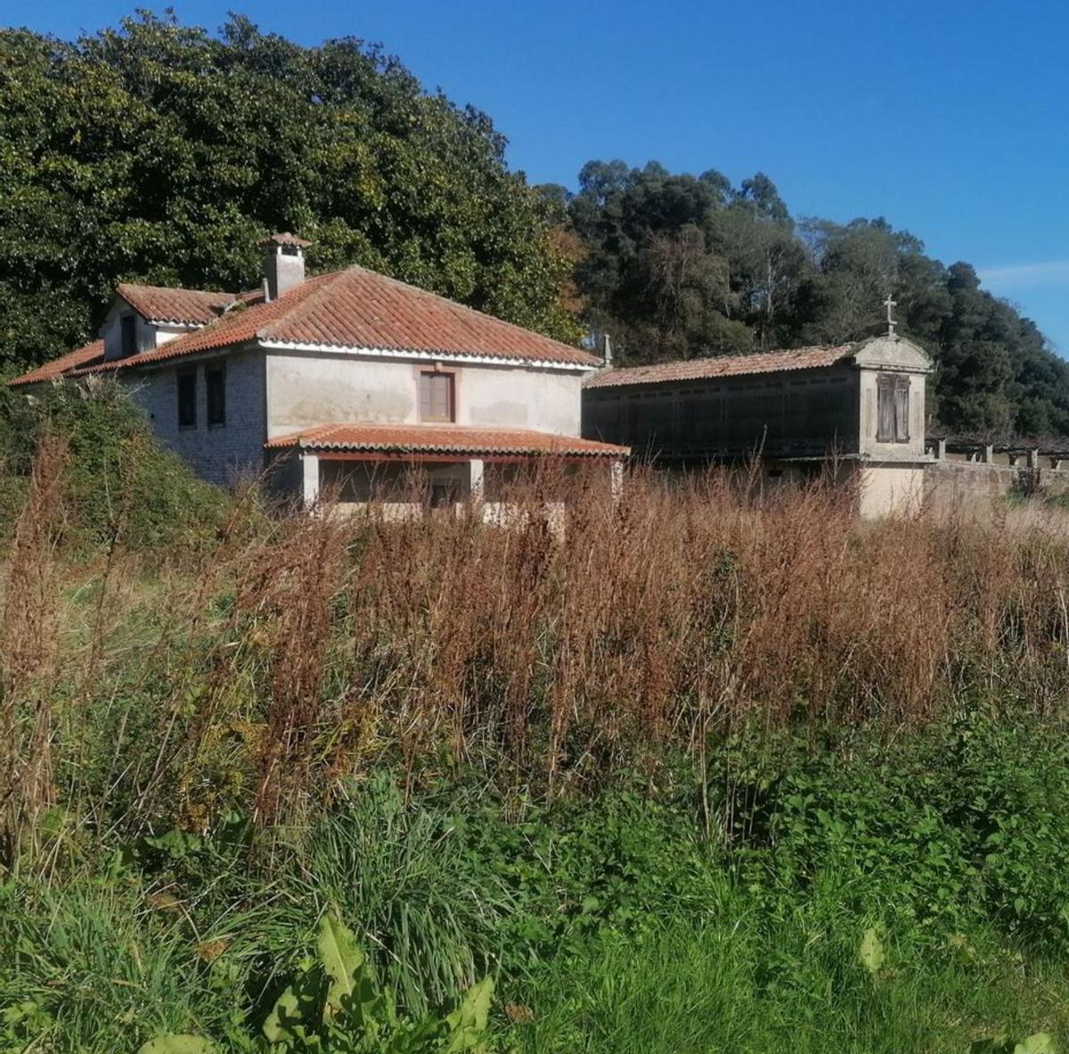 Una pareja posa en 1961 frente a la casa original y el antiguo hórreo.