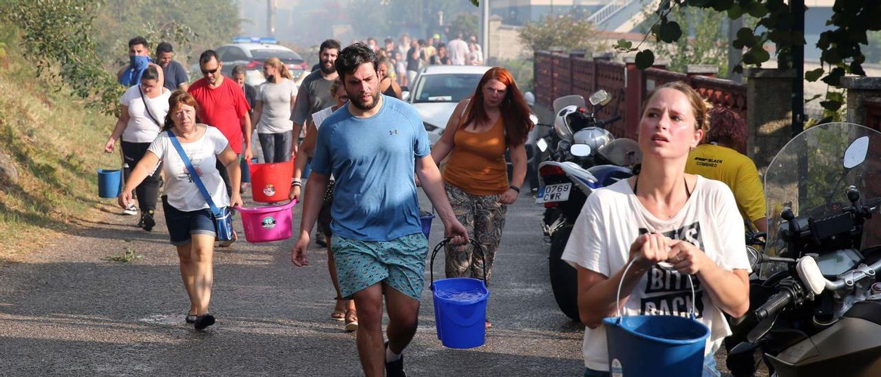 Vecinos portando cubos de agua para combatir el fuego en Meira.