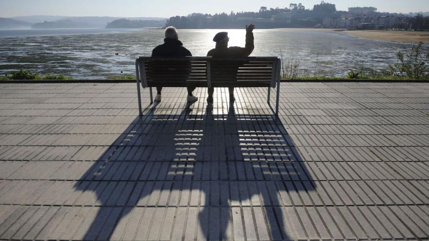Dos hombres toman el sol en un banco del paseo marítimo de Sada en pleno invierno. | C. Pardellas
