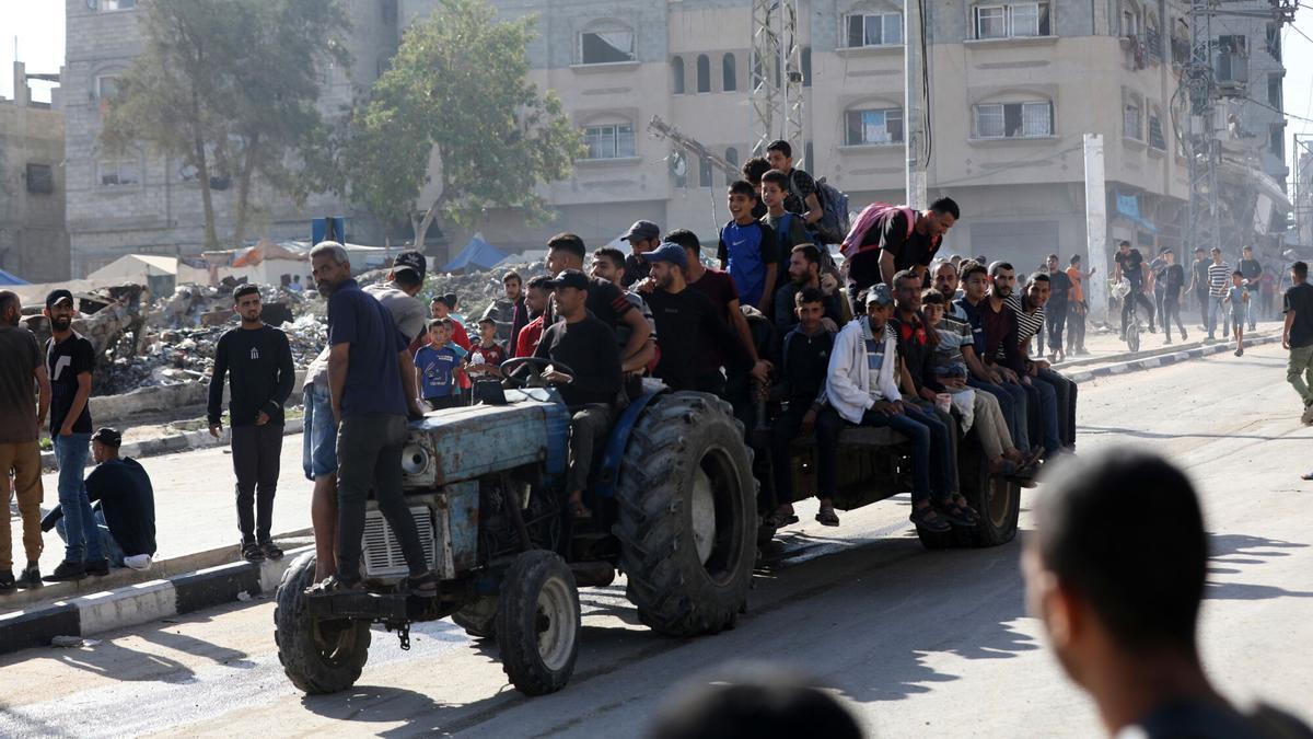 Palestinos desplazados cargados con suministros de ayuda regresan de un centro de distribución de ayuda en el centro de la Franja de Gaza.
