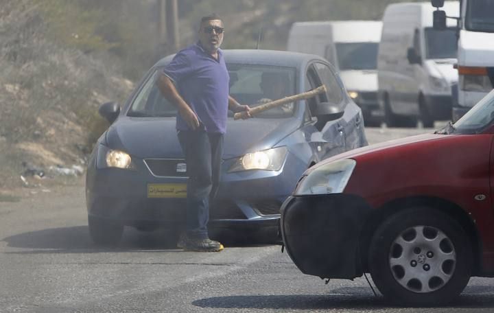 An Israeli motorist holds a club before he was struck by a Palestinian vehicle in the West Bank city of Hebron