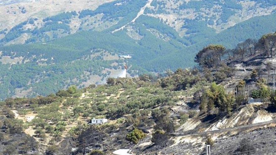 En la primera imagen, la zona afectada por el incendio, ayer. En la segunda, un helicóptero trabajando en las tareas de extinción.