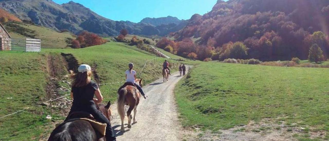 Turistas camino de Lago del Valle, en Somiedo, en una ruta a caballo.