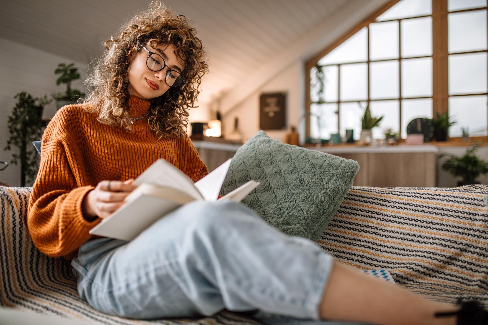 Mujer lee libro en un sofá