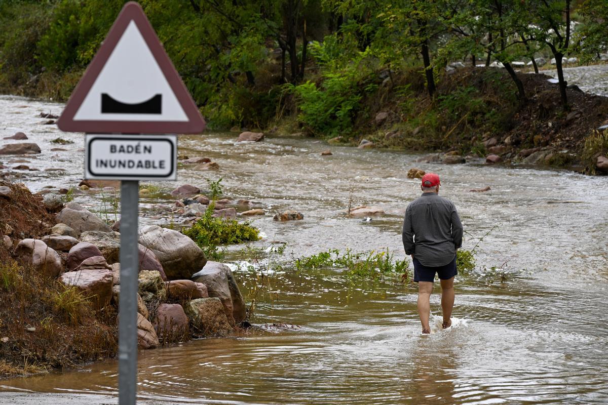 Un hombre cruza un badén inundable en la Comunitat Valenciana; el litoral sur de Alicante estará mañana en alerta roja.