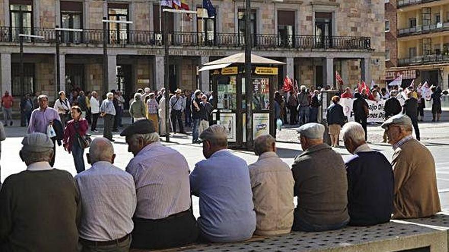 Jubilados observan una manifestación de pensionistas en la plaza de la Constitución.