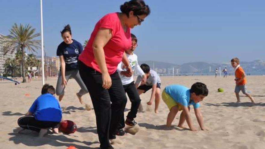 Niños practicando rugby con sus padres en la playa.