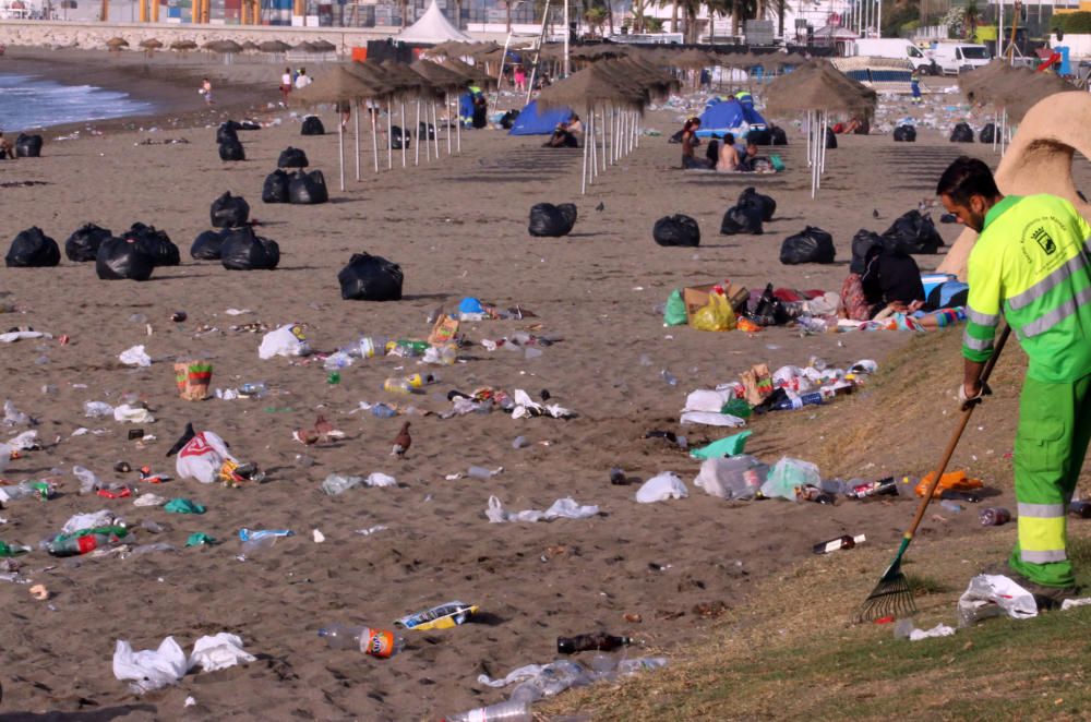 Los operarios de los servicios de limpieza trabajan para dejar la playa en óptimas condiciones tras una larga noche de fiesta en la arena