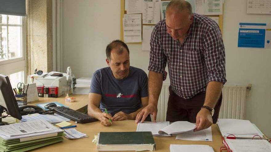 Calvo (dcha.), ayer, supervisando unos documentos junto a un trabajador del Concello. // Bernabé/Ana Agra