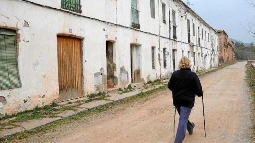 Una dona passeja pel carrer de les cases de la Colònia Antius, la majoria de les quals presenten un aspecte demacrat