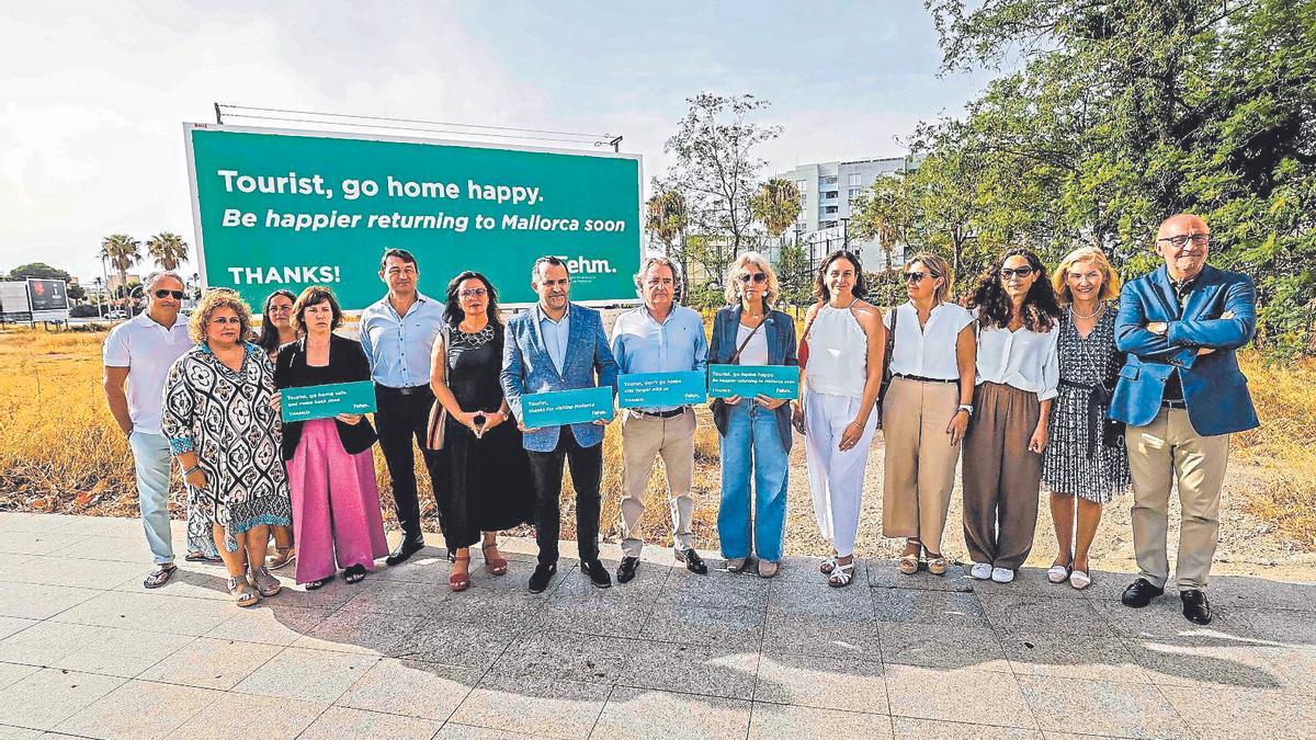 Hoteleros posan junto a una de las vallas de la campaña de la FEHM para contrarrestar la turismofobia