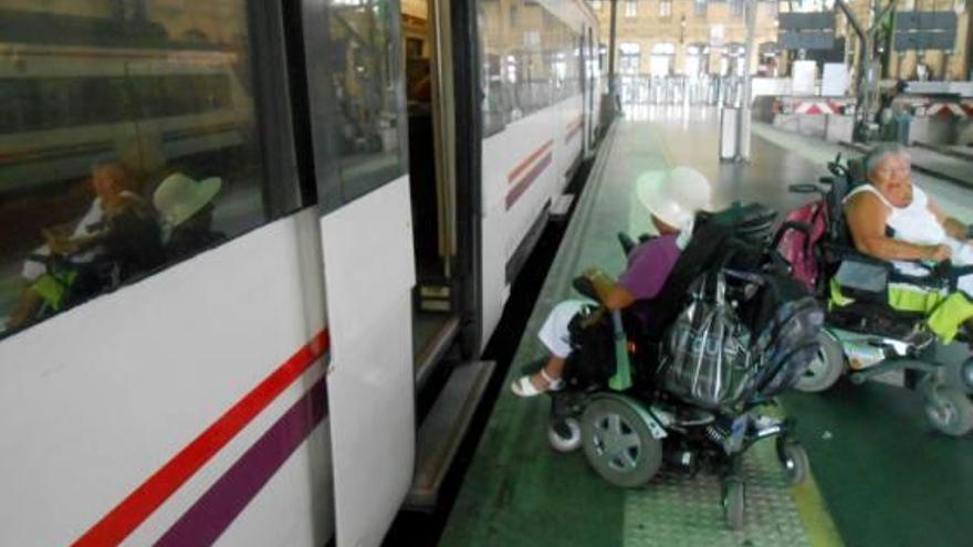 Personas con discapacidad ante uno de los trenes de Cercanías sin adaptar.