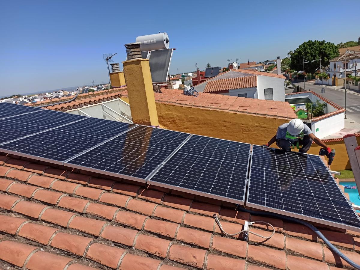 Un instalador ultima un sistema de autoconsumo fotovoltaico en una vivienda.