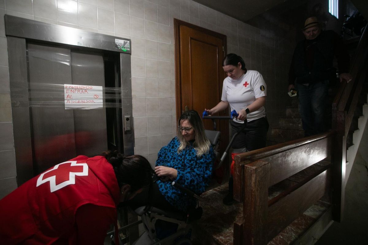 Bajan a Carol, que va en silla de ruedas, a pulso desde el cuarto piso tras la dana.