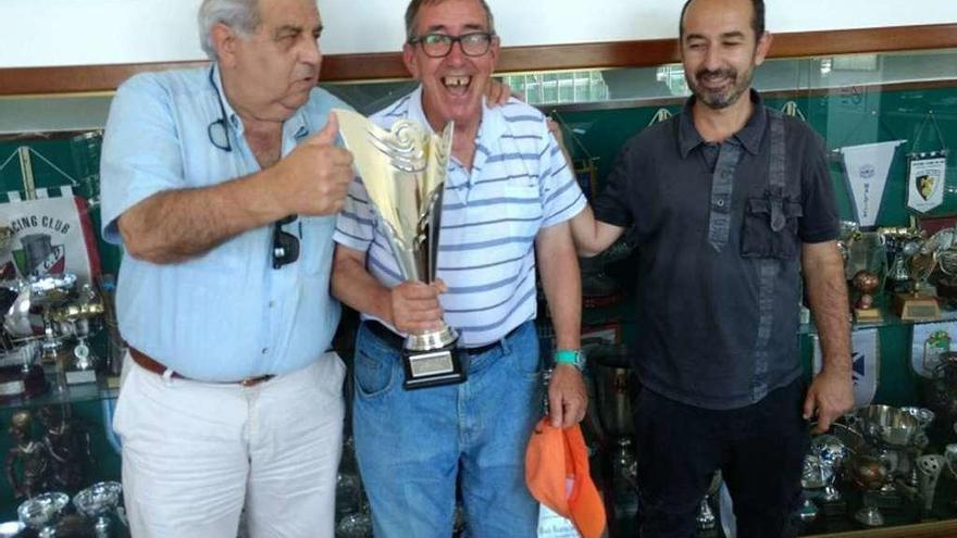 El trofeo, dedicado al aficionado más fervoroso del Rápido | El Rápido de Bouzas recibió en la pasada Gala do Fútbol Galego, celebrada en Santiago, un trofeo con motivo de su ascenso a Segunda División B. El presidente del Rápido, Manolo Seoane, y el director deportivo, Alex Martínez, lo han puesto en las vitrinas y con motivo del acto invitaron a uno de los aficionados más populares y fervorosos que tiene la entidad aurinegra, Mundo, que posa en la imagen con el trofeo y los dos dirigentes boucenses.