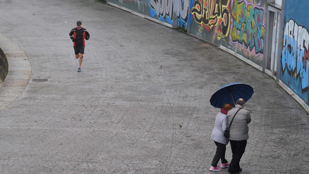 Varias personas con capucha y paraguas en el Andén de riazor.