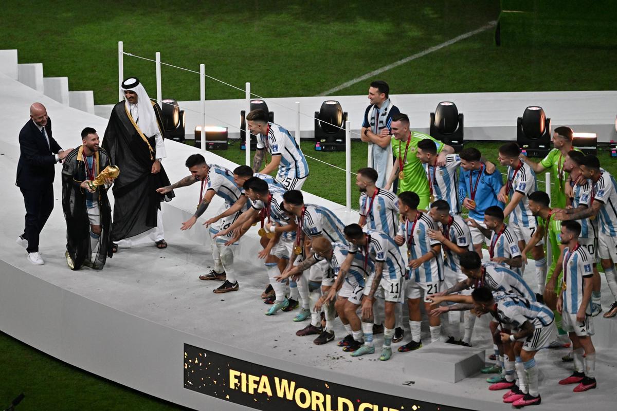 Lusail (Qatar), 18/12/2022.- Lionel Messi of Argetnina (2-L) holds the world cup trophy next to FIFA President Gianni Infantino (L) and Sheikh Tamim bin Hamad Al Thani, the Emir of Qatar (3-L) as players of Argentina gesture during the awards ceremony after the FIFA World Cup 2022 Final between Argentina and France at Lusail stadium, Lusail, Qatar, 18 December 2022. (Mundial de Fútbol, Francia, Estados Unidos, Catar) EFE/EPA/Noushad Thekkayil