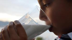 Un niño, bebiendo un vaso de leche.
