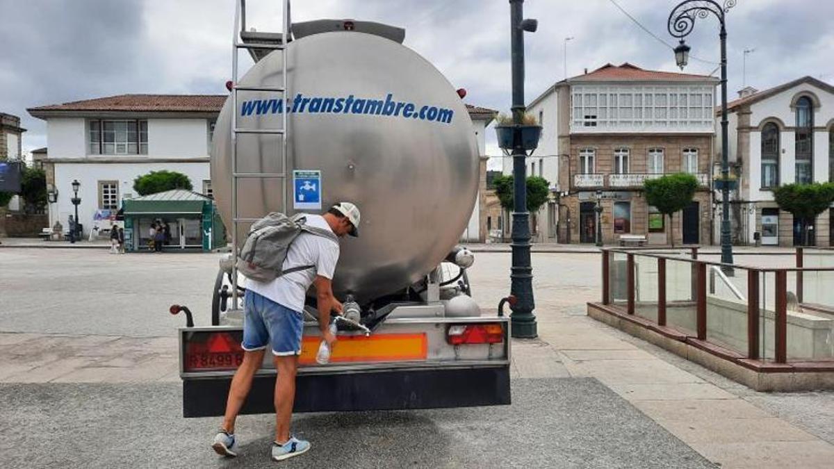 Un turista rellena una botella de agua, ayer, en la cisterna de la plaza Hermanos García Naveira.