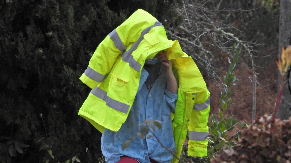 La joven, aún con el pijama hospitalario de Psiquiatría, se cubre con un impermeable durante el rastreo de los restos humanos en su finca.