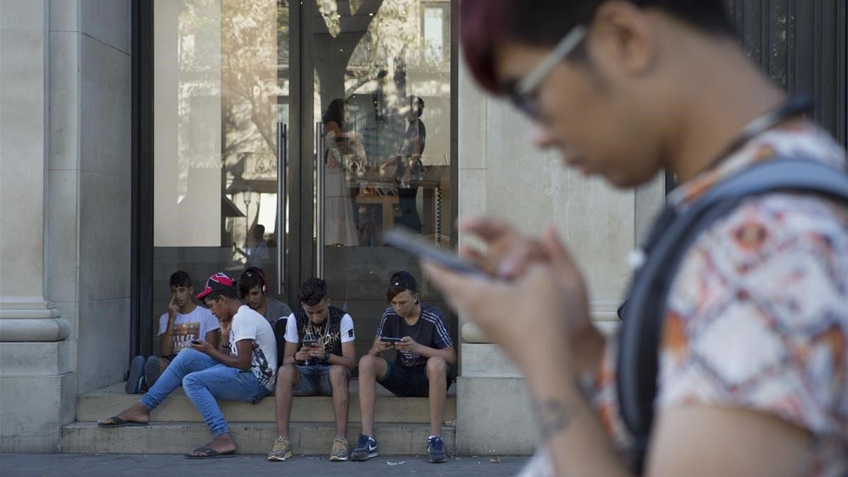 Jóvenes con sus teléfonos móviles en Barcelona, el 12 de agosto del 2016